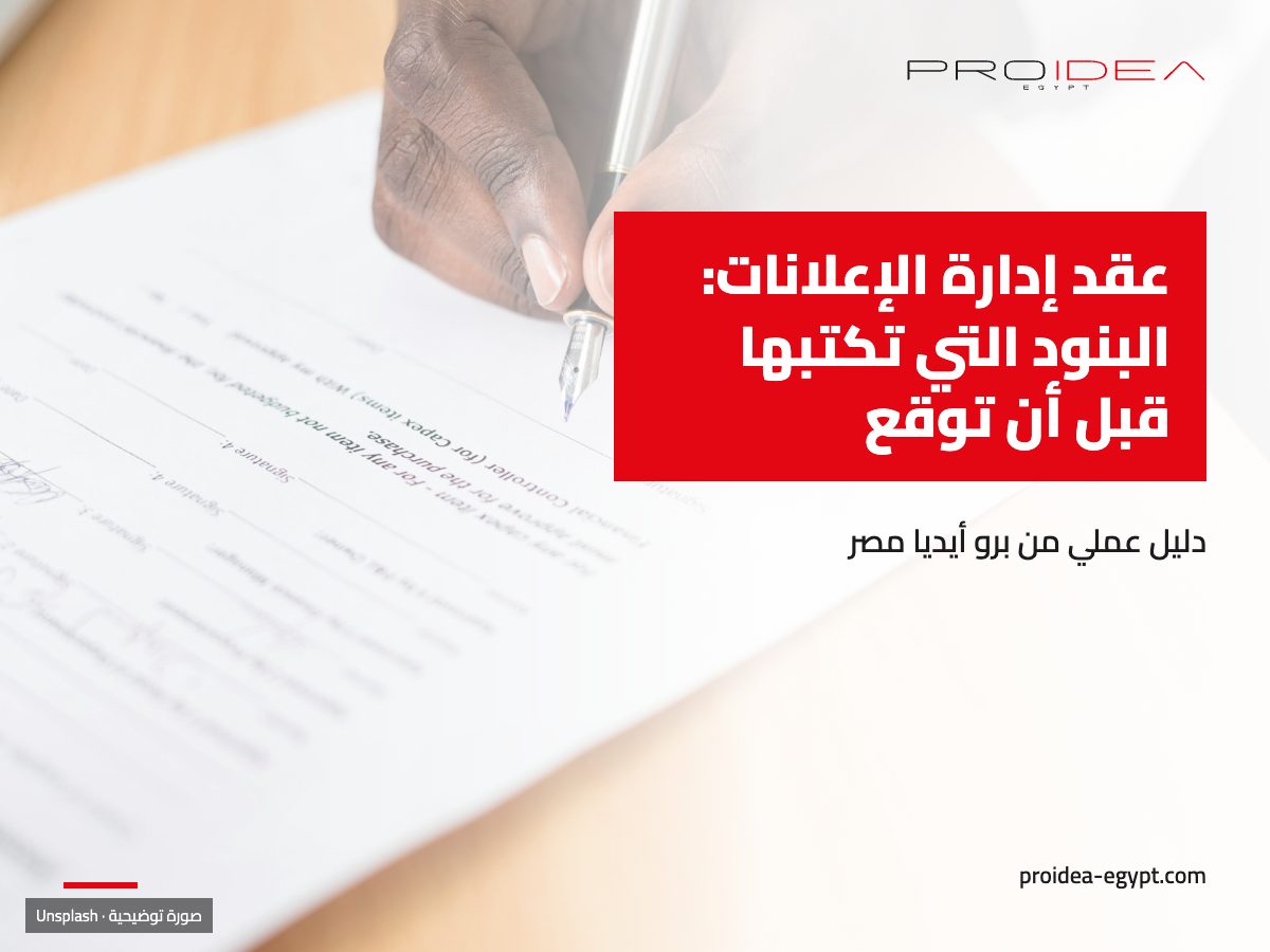 صورة توضيحية لمقال «عقد إدارة الإعلانات»: يد تكتب بقلم على ورقة عقد فوق مكتب خشبي